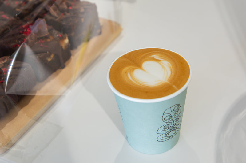 Cup of coffee with latte art on a white surface, with a blurred background