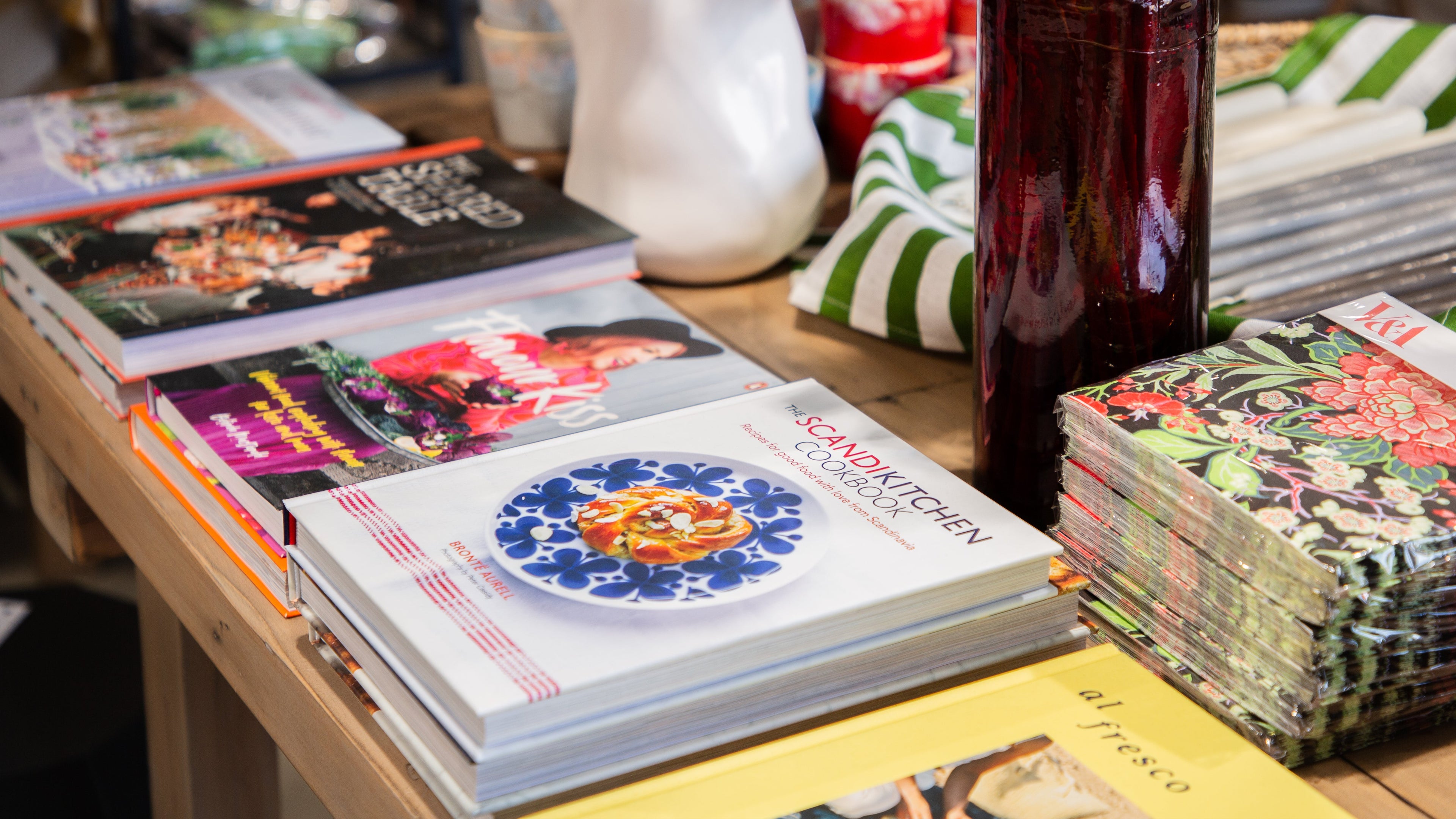 Table with cookbooks, a vase with plants, and other items in a casual setting.