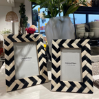 Two black and white chevron patterned picture frames with a vase of flowers in the background.